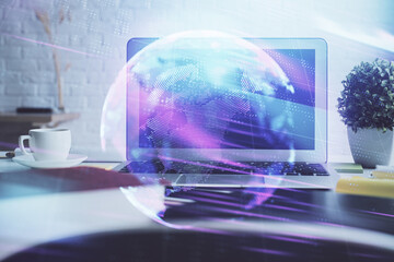 Computer on desktop in office with technology theme hologram. Double exposure. Tech concept.