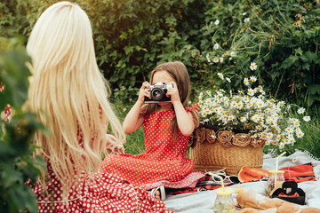 Young Mom with her Little Daughter Dressed Alike in Red Polka Dot Dress, Having Fun Time on a Picnic in the Field, Motherhood and Childhood Concept