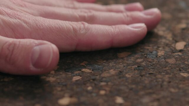 Slow motion man hands touch dark cork surface with oil finish