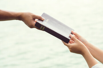 Man hand giving the Bible to women.Concept of giving