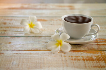 Obraz na płótnie Canvas Plumeria flowers and hot coffee cups on wooden table