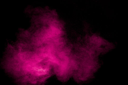 Pink dust particles splash on black background.Pink powder splash.