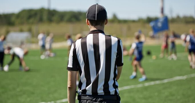 Female sports team playing rugby at the stadium. Silhouette of the referee watching the match. The support group of players with a flag. Concept of sports and competitions. Flag football