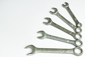 Five different wrenches lie on the right on a white background