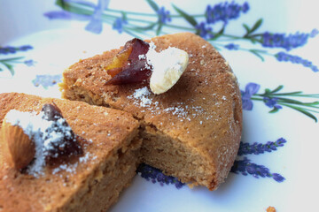 Indian home baked egg less spongy floor and coffee flavored cake called atta cake garnished with almond, cashew and Arabian dates in a lavender white plate