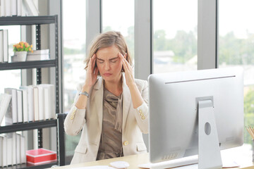 Businesswoman so tried headache and suffering stress working at office computer table.