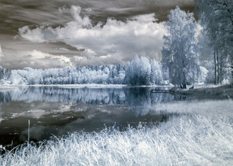 landscape photographed with infrared filter, trees look like in winter, beautiful cloud reflections in the water, surreal landscape