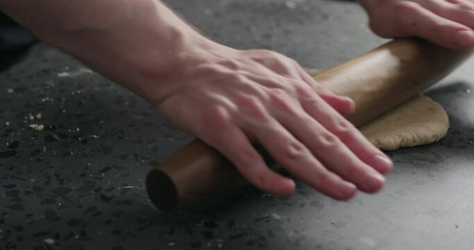Slow motion man rolling dough on concretre countertop