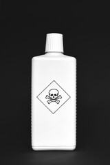 White bottle with poison skull sign on black background