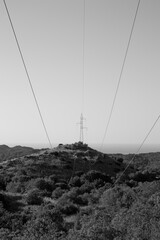 Power line on top of a hill with a clear sky and forest under the hill AM