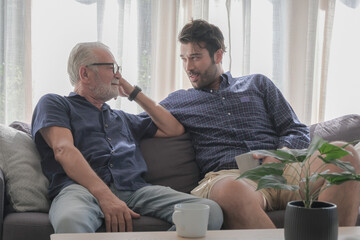 Old father and son happy talking in cozy living room house. Family spending time or sharing story together concept.