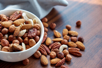 Wooden bowl with mixed nuts on table top view. Healthy food and snack. Walnut, pistachios, almonds, hazelnuts and cashews.