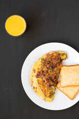Homemade Denver Omelette on a white plate on a black surface, top view. Flat lay, overhead, from above.
