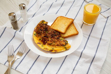 Homemade Denver Omelette on a white plate on cloth, side view.