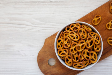 Crispy Pretzel Crackers in a Gray Bowl on a white wooden background, top view. Copy space.