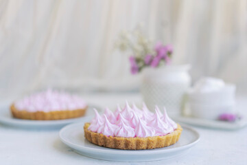 Mini tartlet with fruit jam and pink meringue. Tart with Italian meringue cream on white plate on...