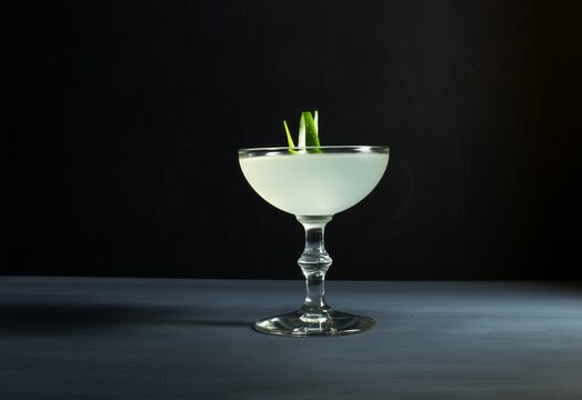 Classic Gimlet Cocktail, Lime Garnish, Coupe Glass Isolated Against A Dark Grey And Black Background
