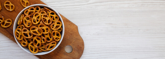 Crispy Pretzel Crackers in a Gray Bowl on a white wooden background, top view. Flat lay, overhead, from above. Copy space.