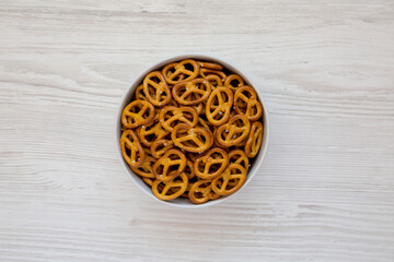 Crispy Pretzel Crackers in a Gray Bowl on a white wooden background, top view. Flat lay, overhead, from above.