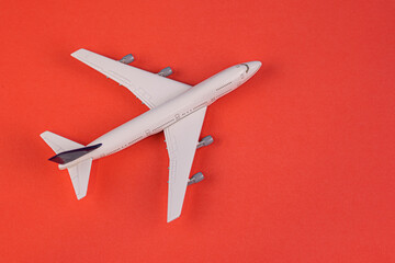 Concept of travel vacation. Top view white toy airplane isolated on red background with copy space. Minimal think.