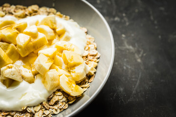Healthy and tasty breakfast with muesli, yogurt, bananas and honey. Selective focus.
