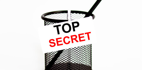 Word TOP SECRET on a leaf on a glass for pencils .The concept of working in an office .