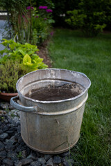 Fototapeta premium Metal bucket filled with water and dirt on the bottom of it in a park AM