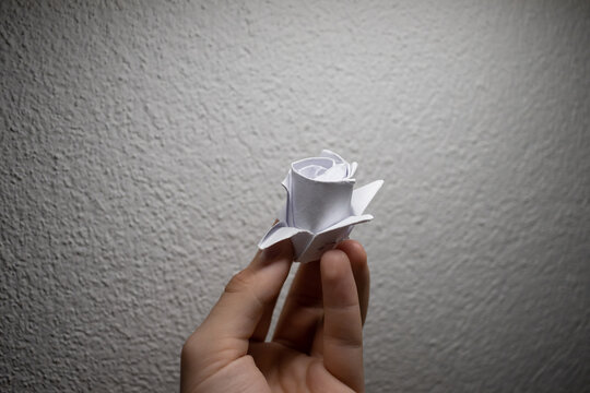 Origami rose made of white paper held in a hand AM