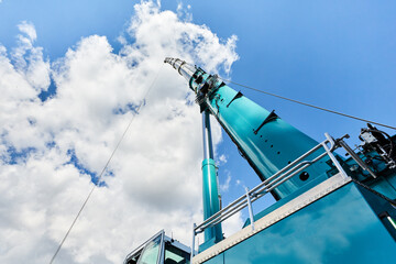 truck crane with outstretched boom on blue sky background