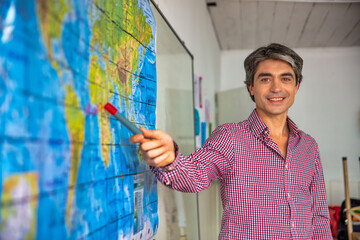 Happy confident teacher explaining geography lesson at school