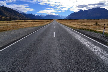 Straight road leading towards a snow capped mountain in New Zealand