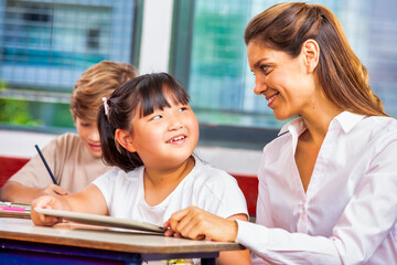 Confident female teacher in the multi ethnic elementary classroom. Back to school concept