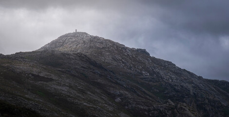 Marco no cimo da montanha com nuvens dramáticas