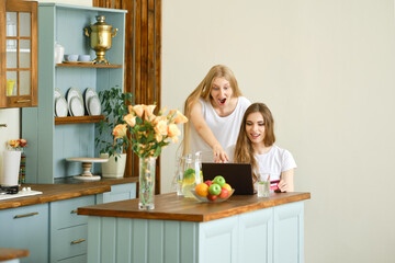 Two young women making online shopping, finding and discussing goods