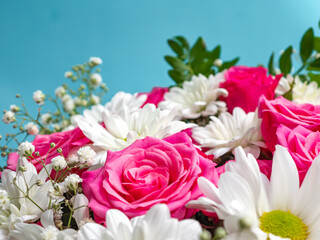 Beautiful pink roses and white daisies in a box on a blue background.