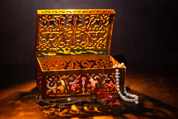 Wooden box with patterns. In the box are gold jewelry rings, chains and jewelry stones pearls.