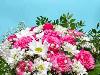 Beautiful pink roses and white daisies in a box on a blue background.
