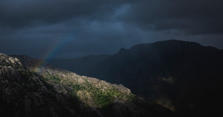 Fototapeta na wymiar Paisagem natural dramática de raio de sol montanhas e arco íris