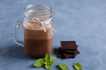 Chocolate cocktail, smoothie in a glass jar with a handle on a gray background. Cool desserts in...