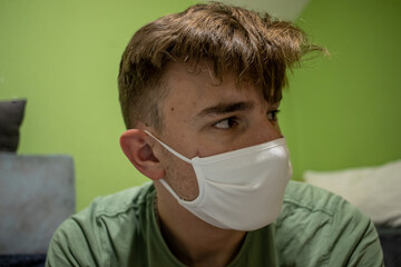 Young male with light brown hair wearing a white medical mask having a devastated and worried look...