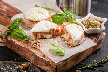 Salmon cutlets with cheese, walnuts, pesto and basil on a wooden cutting board. Delicious and healthy seafood dishes. Cooking like in a restaurant