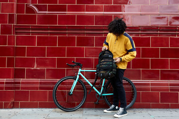 Fototapeta na wymiar Millennial holding his bagpack in urban area next to his fixed gear bike.