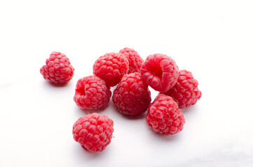 Heap of freah rasberries on the white surface
