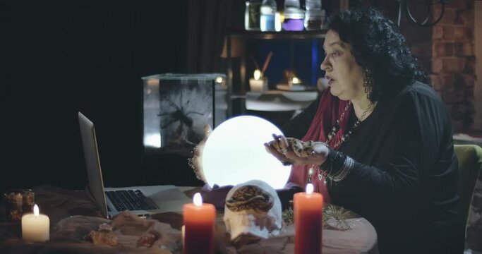 Woman fortune teller performing online seance using laptop