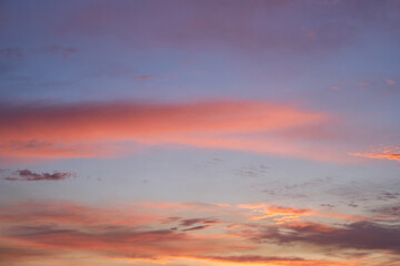 Beautiful evening blue sky at sunset with flaming bright light clouds. A warm summer evening at sunset.