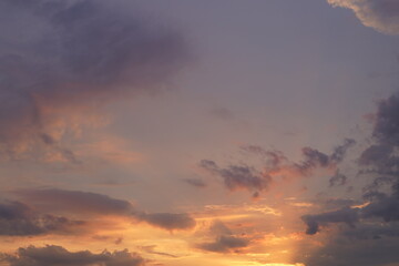 Beautiful evening blue sky at sunset with flaming bright light clouds. A warm summer evening at sunset.