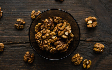 Walnut in a smale plate with scattered shelled nuts and whole nut which standing on a wooden vintage table. Walnuts is a healthy vegetarian protein nutritious food. Walnut on rustic old wood.