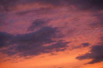 Beautiful evening blue sky at sunset with flaming bright light clouds. A warm summer evening at sunset.