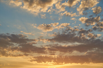 Beautiful evening blue sky at sunset with flaming bright light clouds. A warm summer evening at sunset.