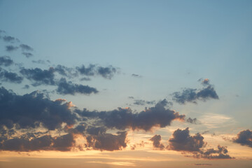 Beautiful evening blue sky at sunset with flaming bright light clouds. A warm summer evening at sunset.